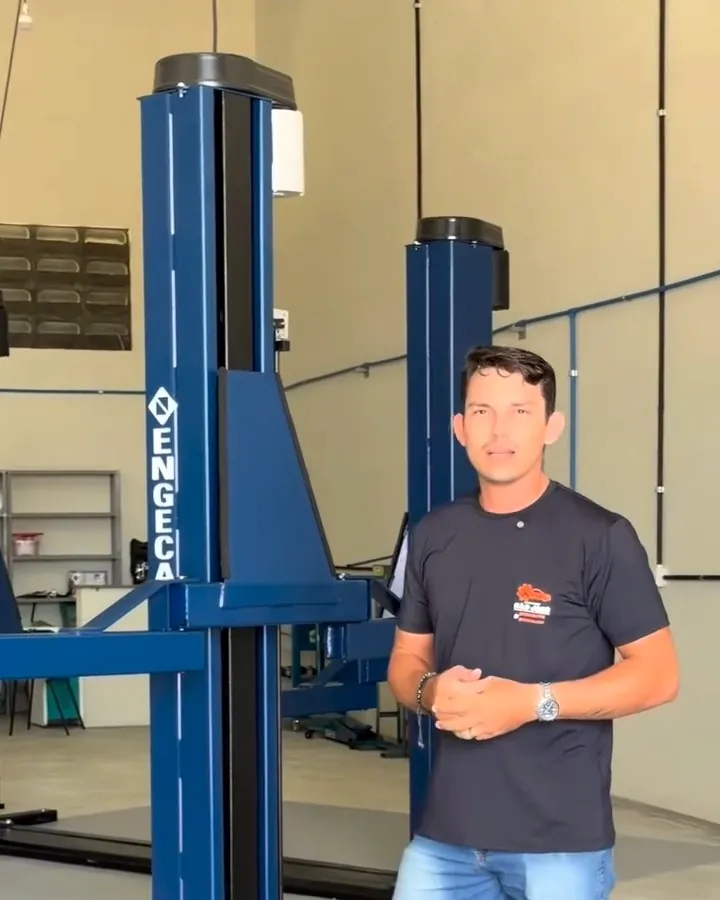 Mecânico da Auto Serviço São José de pé entre os elevadores da oficina