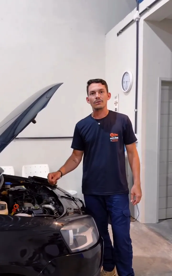 Mecânico ao lado de um carro com o capô aberto